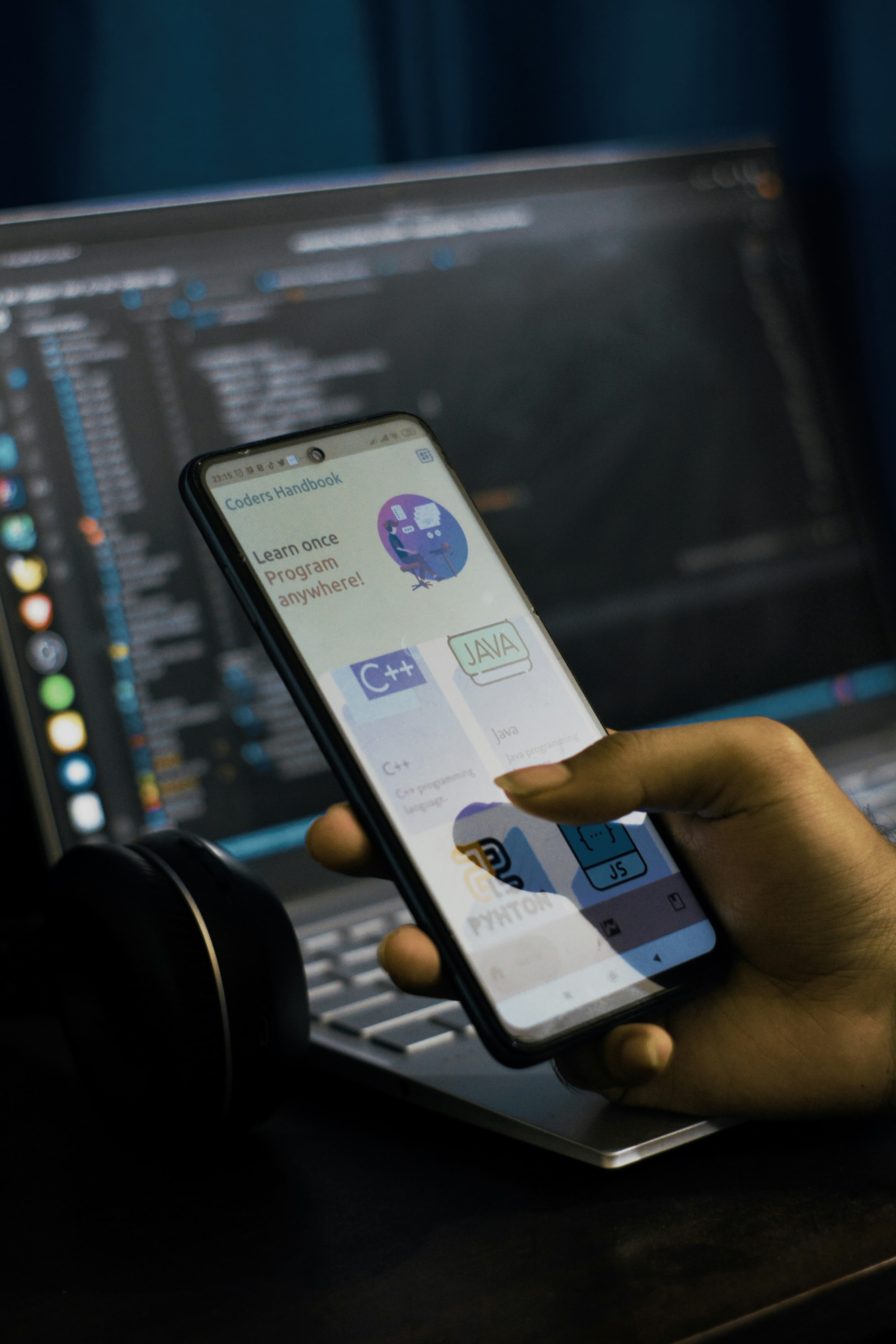Android phone showing a programming handbook over a code editor
