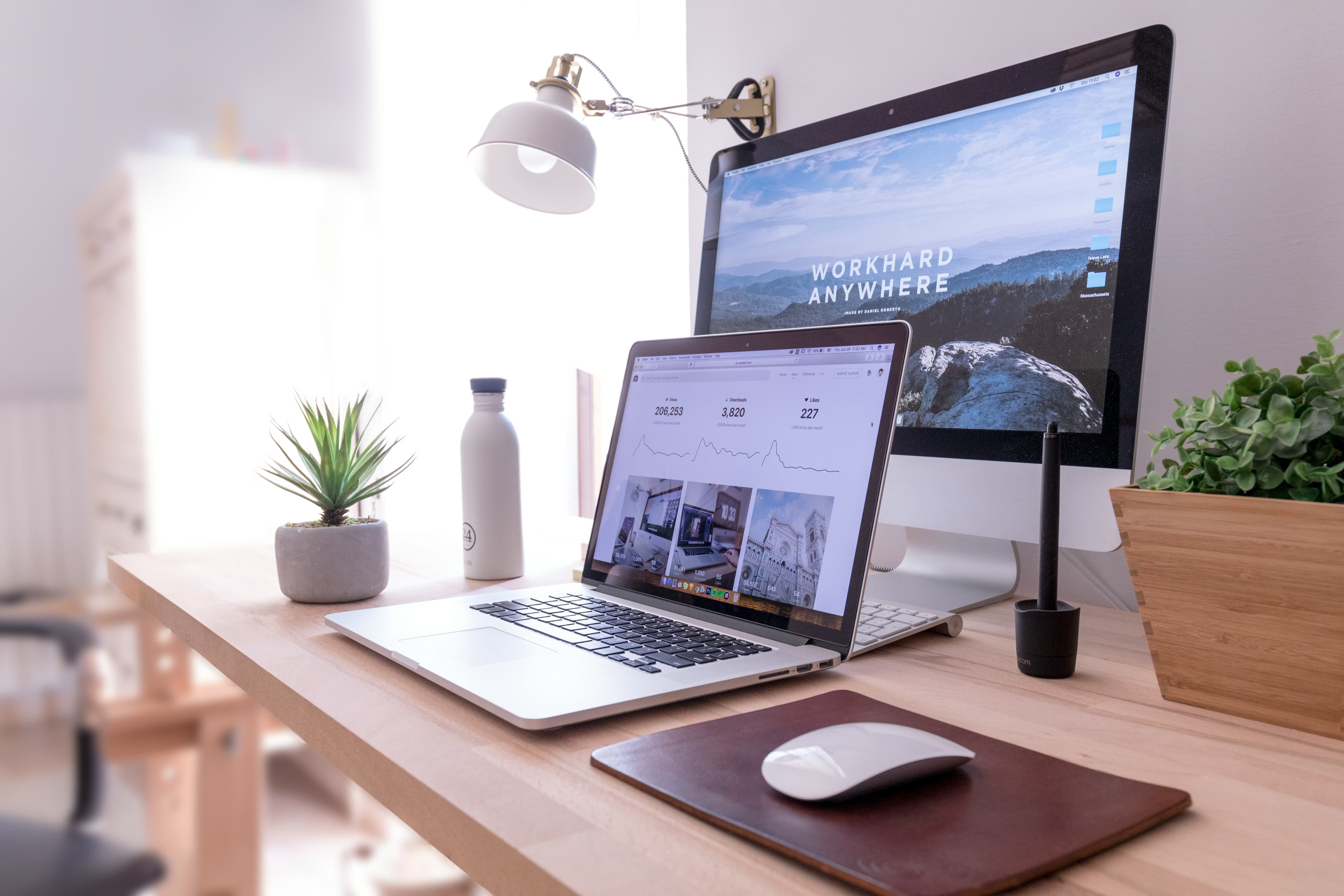 Laptop and desktop displaying different digital interfaces across a bright workspace